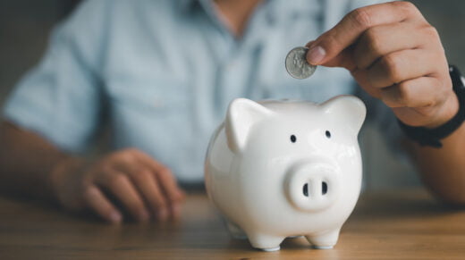 Businessman,hand,putting,coin,in,piggy,bank.,saving,money,concept,