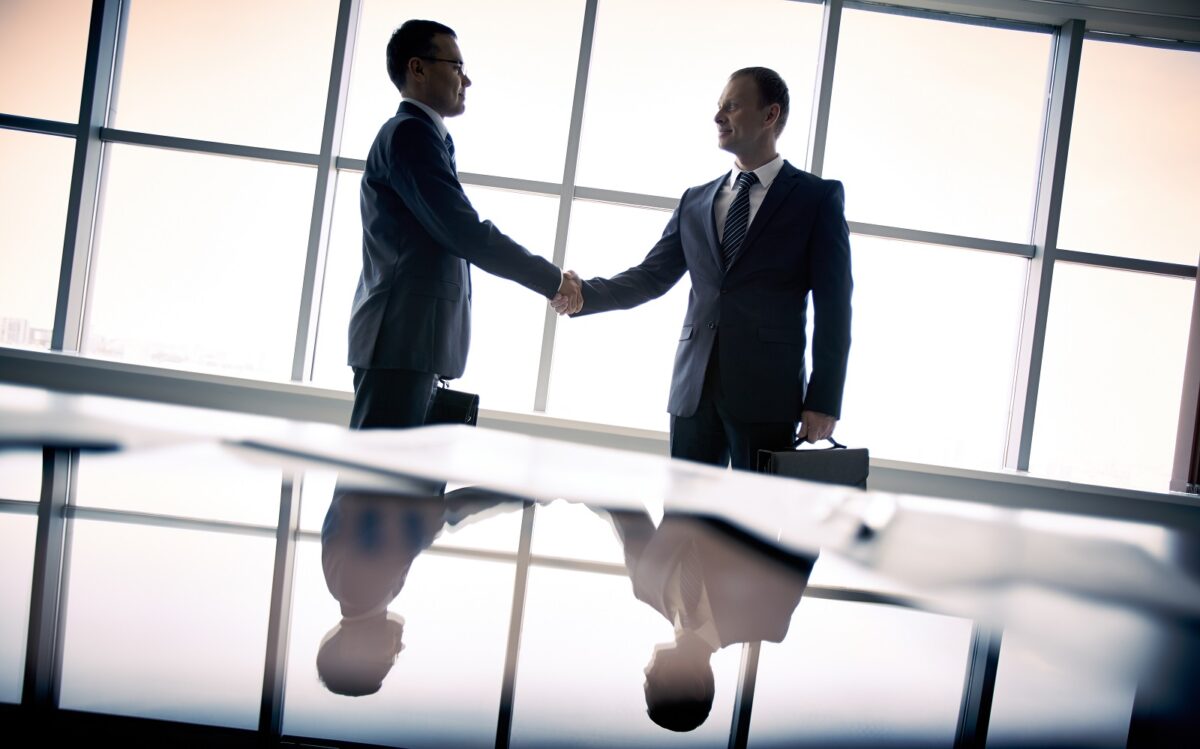 Silhouettes,of,two,businessmen,standing,by,the,window,and,handshaking