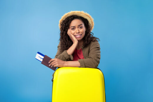 Upset,young,black,woman,holding,passport,and,plane,tickets,,leaning