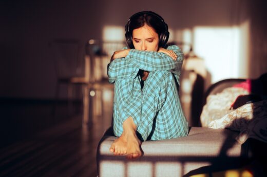 Bored,woman,wearing,headphones,and,pajamas,at,home,unhappy,disappointed