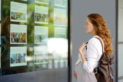 Young,pregnant,woman,exploring,storefront,of,real,estate,agency.,beautiful