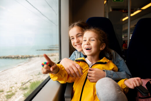 Two,sister,girls,look,out,the,window,of,a,train