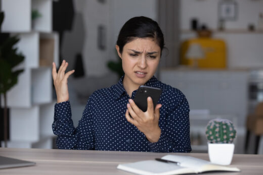 Upset,annoyed,indian,girl,having,problems,with,smartphone,,looking,at