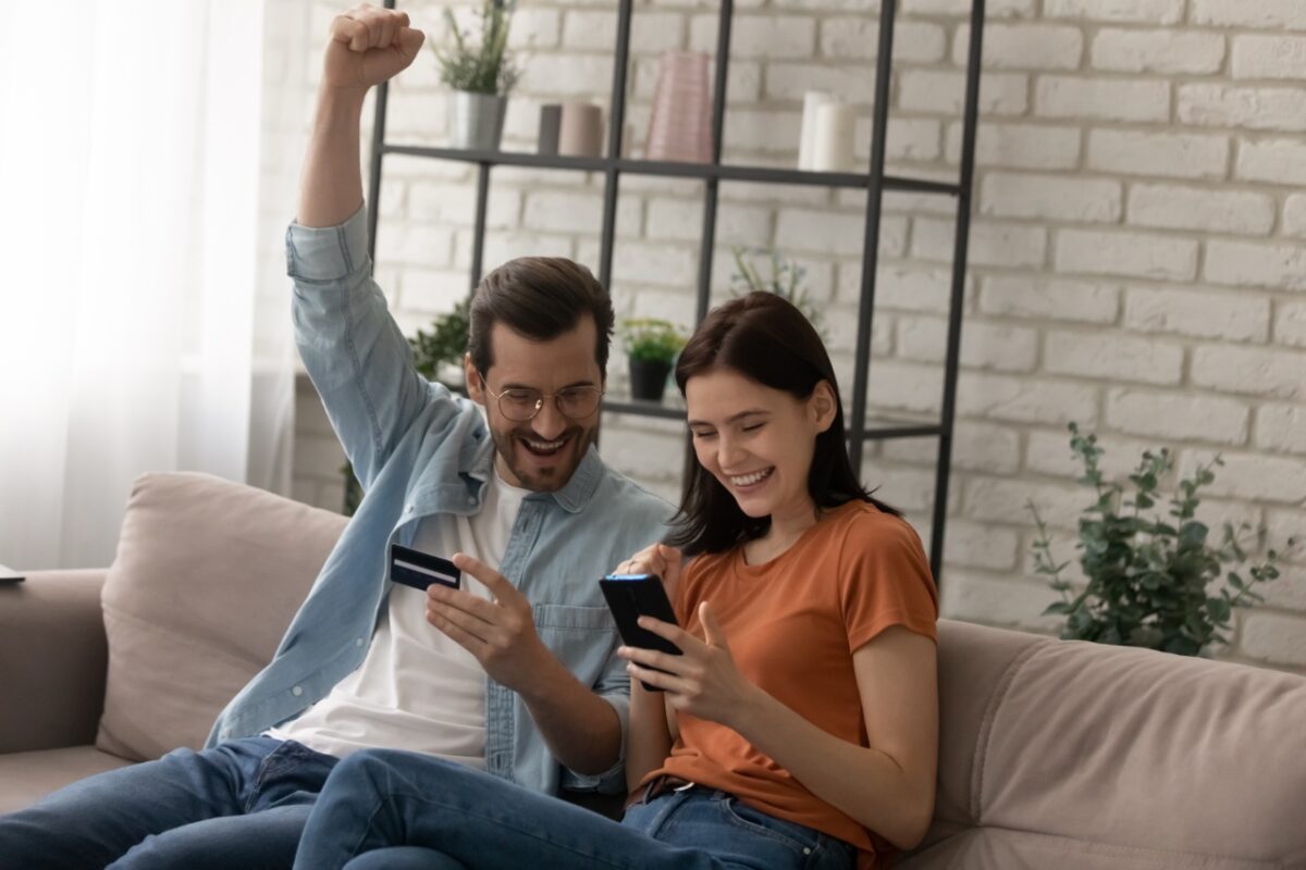 Happy,young,married,family,couple,involved,in,online,shopping,,celebrating