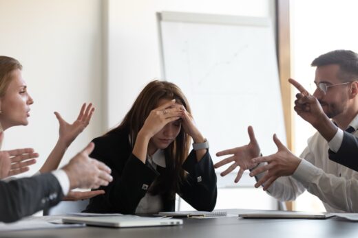 Frustrated,millennial,female,worker,sitting,at,table,with,colleagues,,felling
