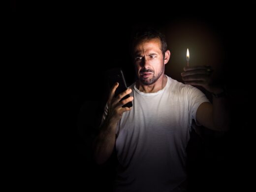 Man,looking,at,his,cell,phone,with,a,match,in